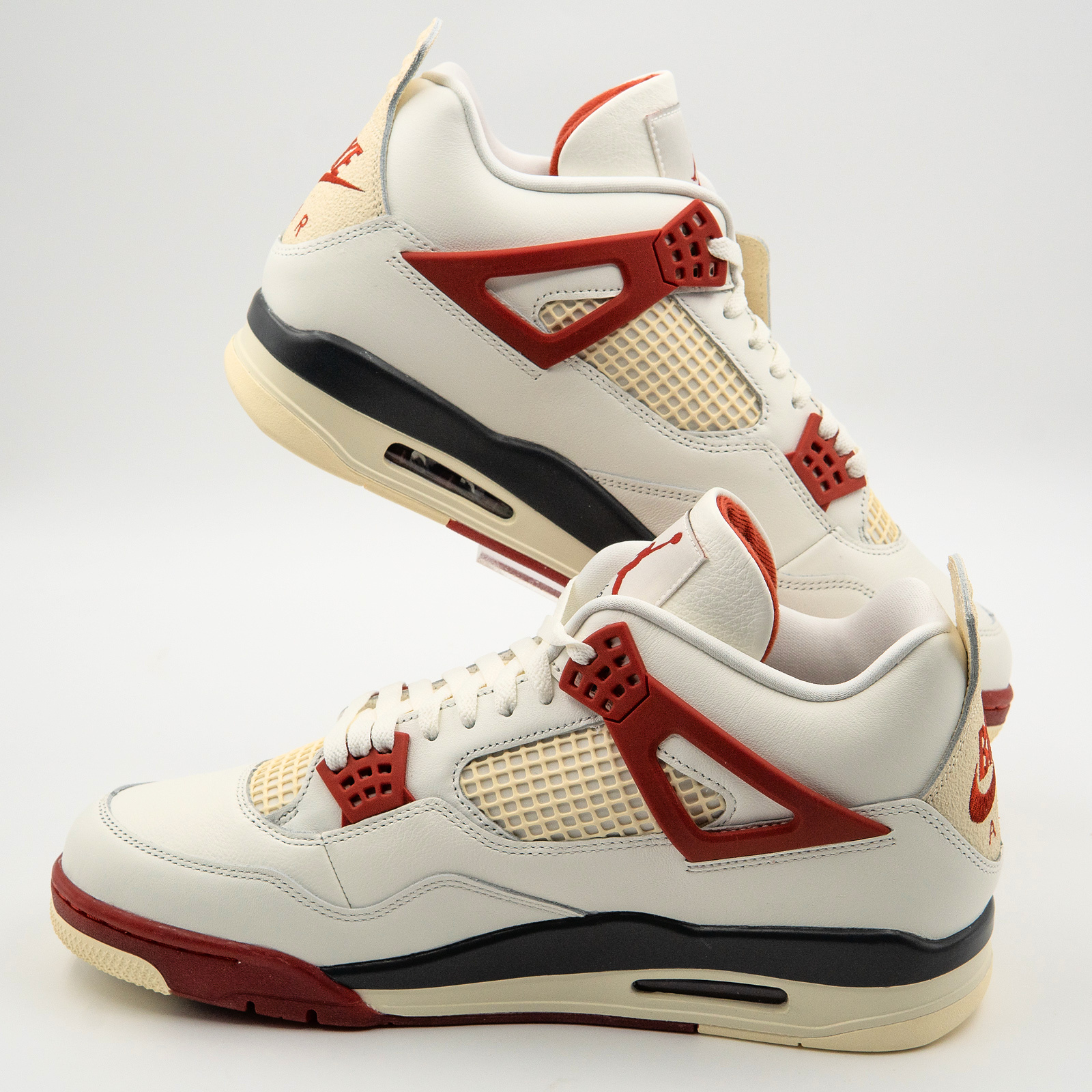 Sail and brick-red Nigel Sylvester Air Jordan 4 Brick After Brick pair in a diagonal side view on a clear display mount